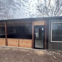 Exterior of a modern building with a covered porch and a glass door.