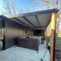 A spa under a dark awning with a concrete patio.