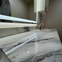 Marble countertop with faucet and lighted mirror.