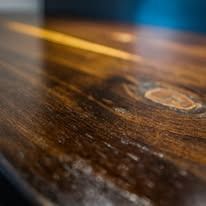 Close-up of a glossy, dark stained wooden surface with visible wood grain and knots.