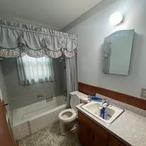 Bathroom with blue curtains, toilet, and sink.