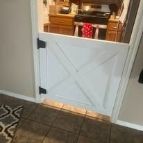 White wooden gate with an X design, attached to a kitchen doorway.