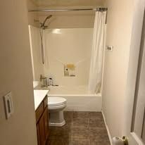 Bathroom with a bathtub, shower curtain, toilet, and sink.