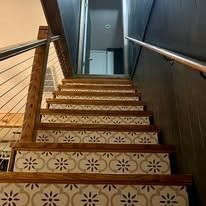Wooden staircase with floral tile treads leading to a door.