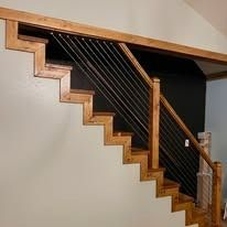 Wooden staircase with black metal cable railing.