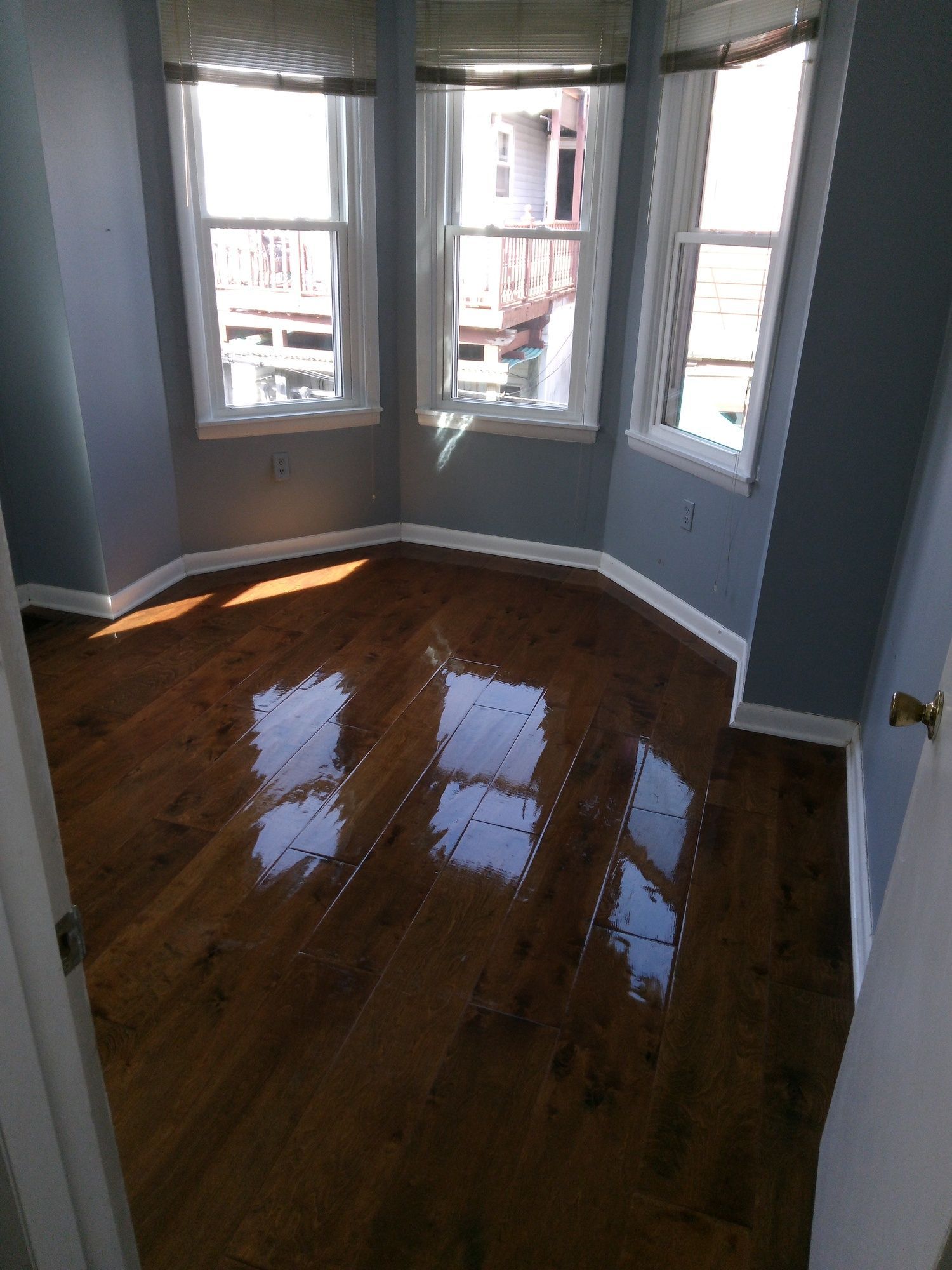 An empty room with hardwood floors and three windows.