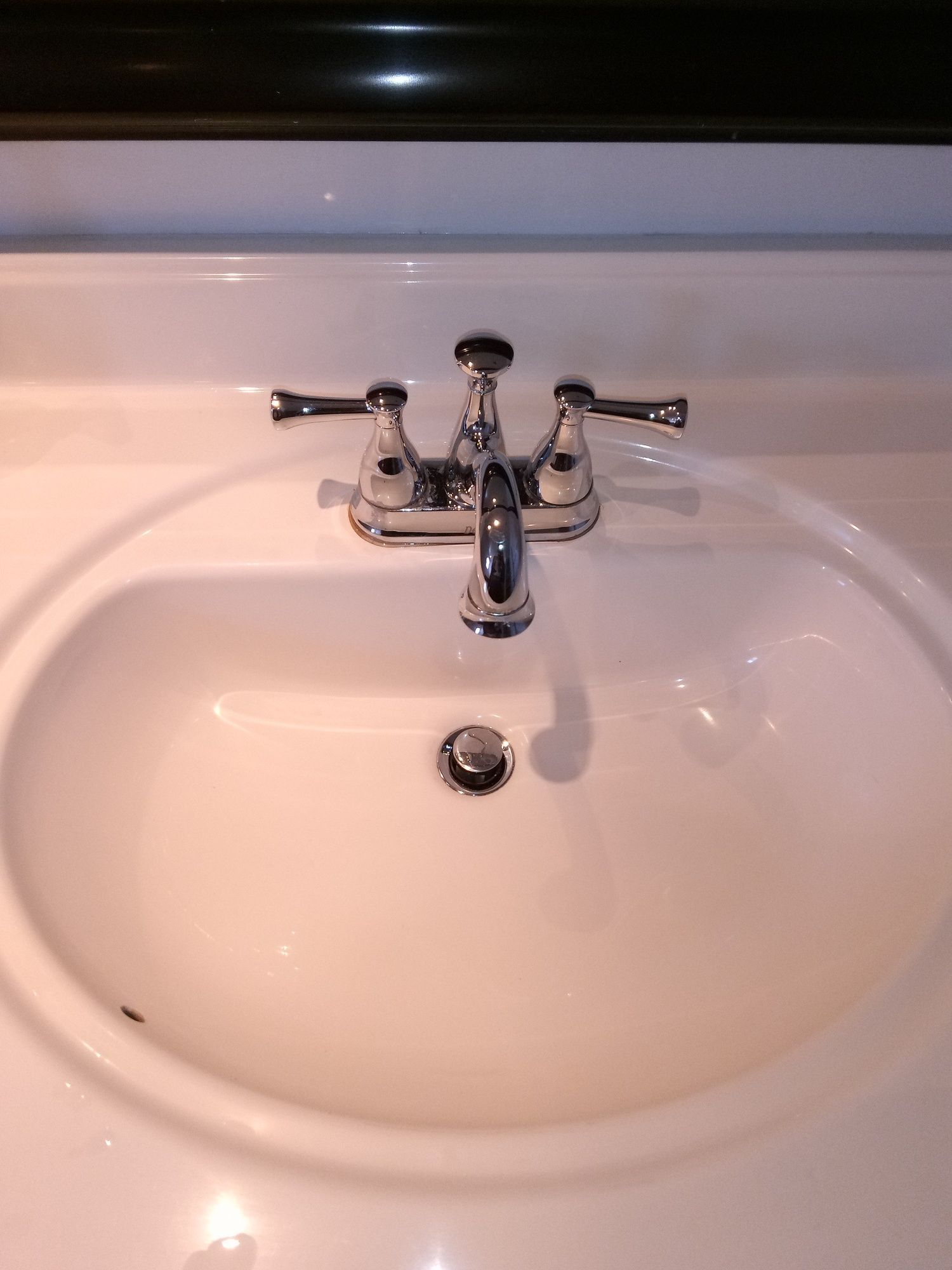 A bathroom sink with a chrome faucet and handles