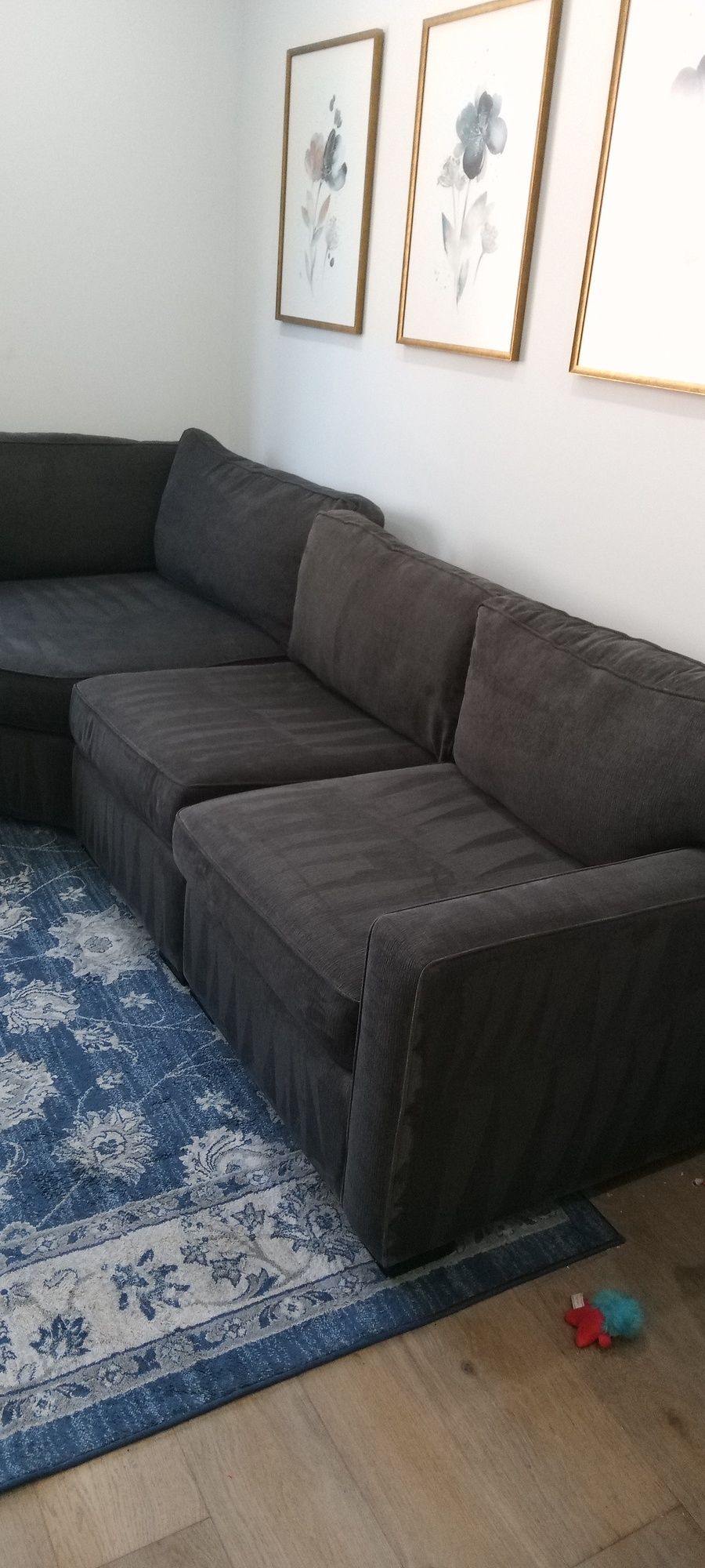 A large sectional couch is sitting in a living room next to a rug.