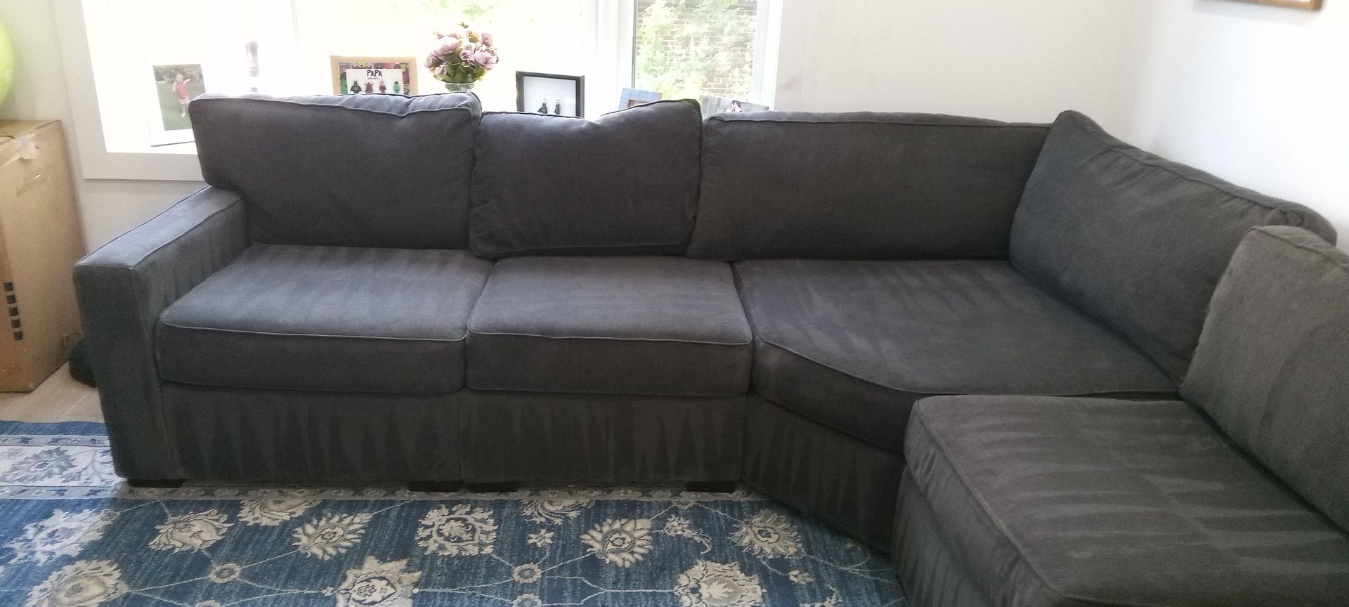 A gray sectional couch is sitting in a living room next to a window.