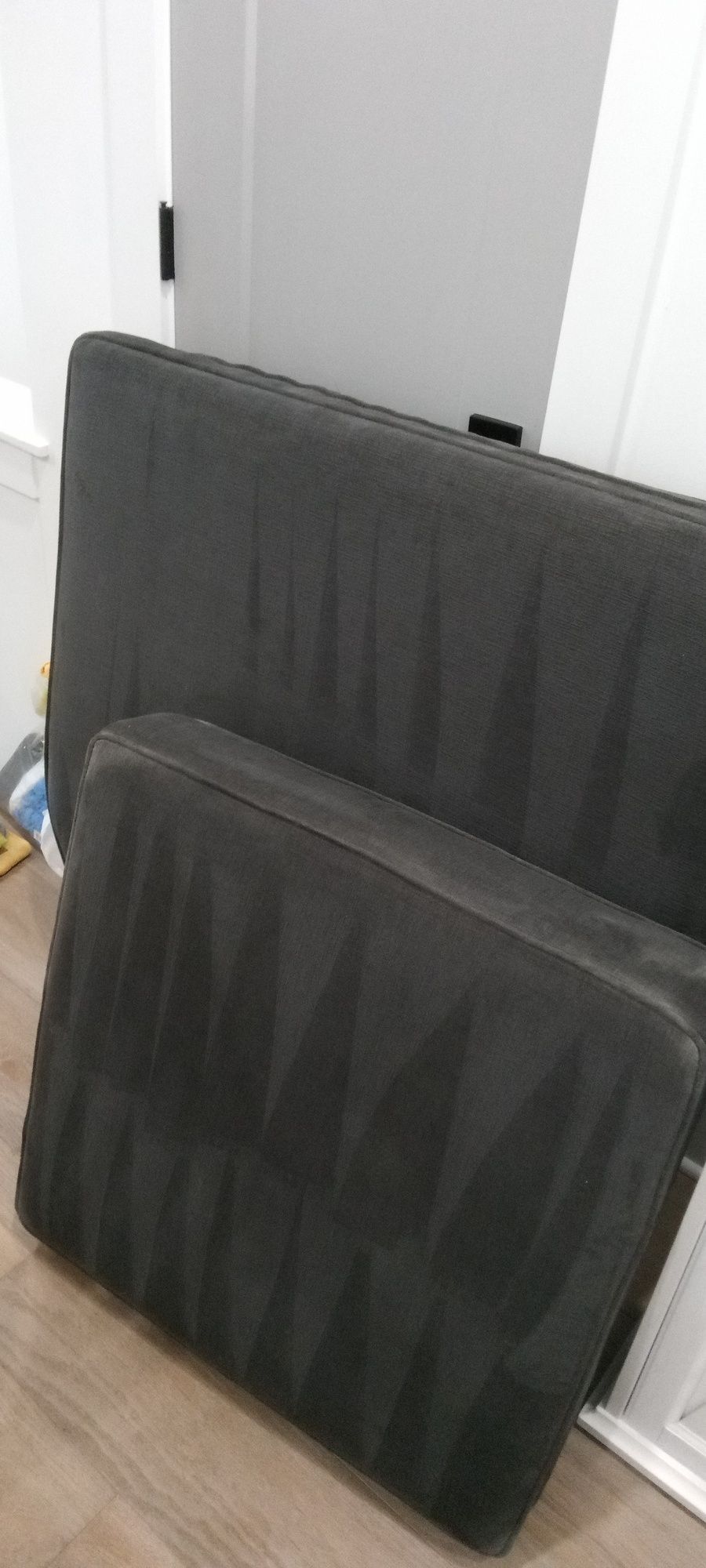 Two mattresses are stacked on top of each other on a wooden floor.