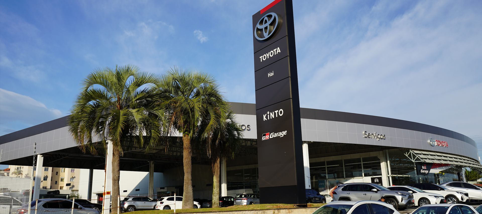 Prédio de uma concessionária Toyota com logotipo e texto em vermelho sob um céu azul.