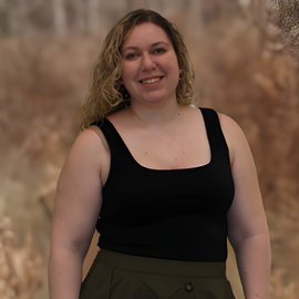 A woman in a black tank top is smiling for the camera