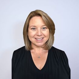 The woman is wearing a black shirt and smiling for the camera.