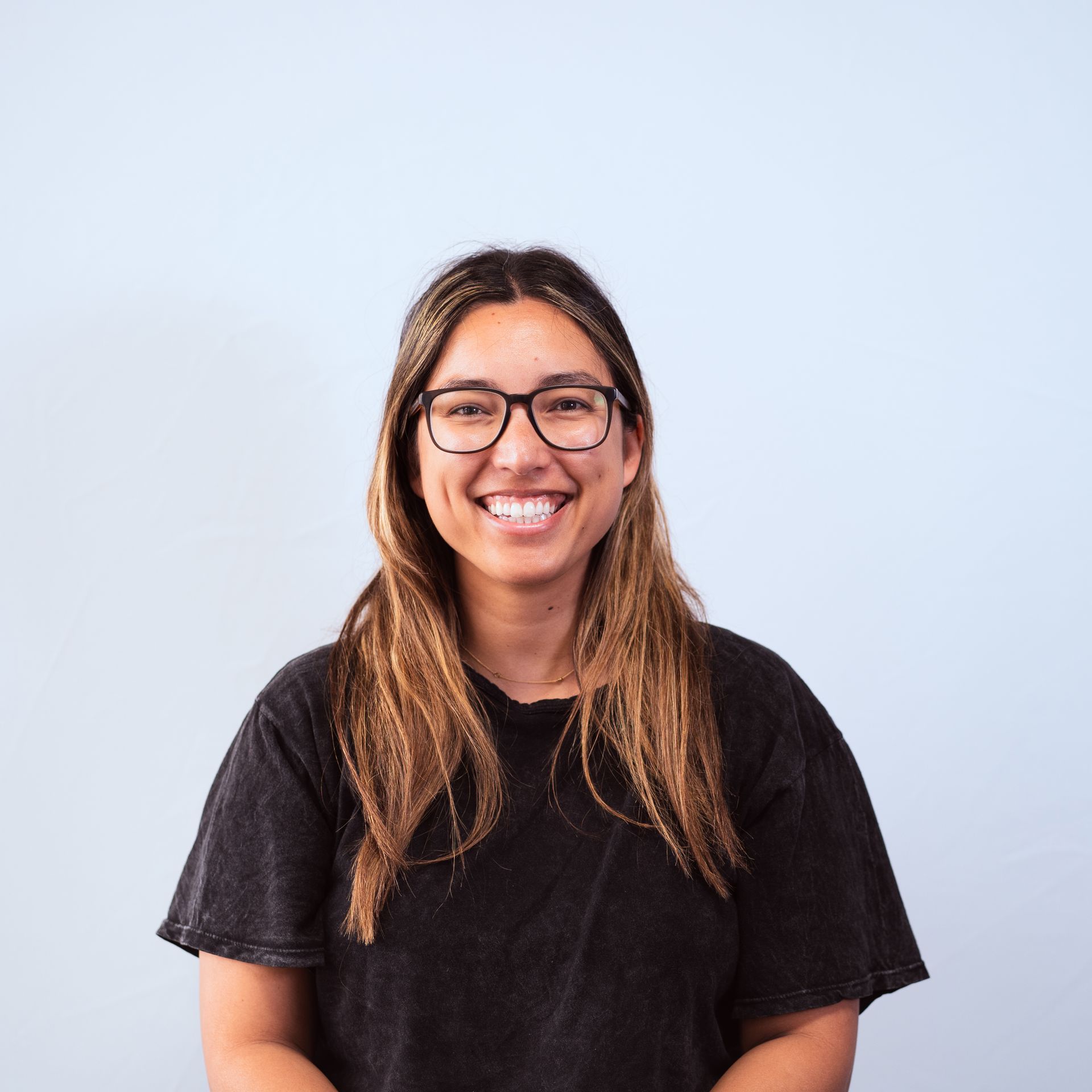 A woman wearing glasses and a black shirt is smiling for the camera.