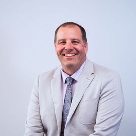 A man in a suit and tie is smiling for the camera