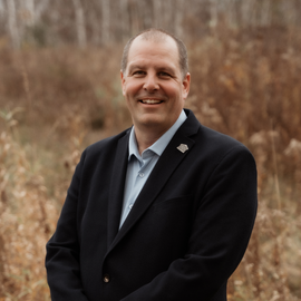 A man in a suit and tie is smiling for the camera