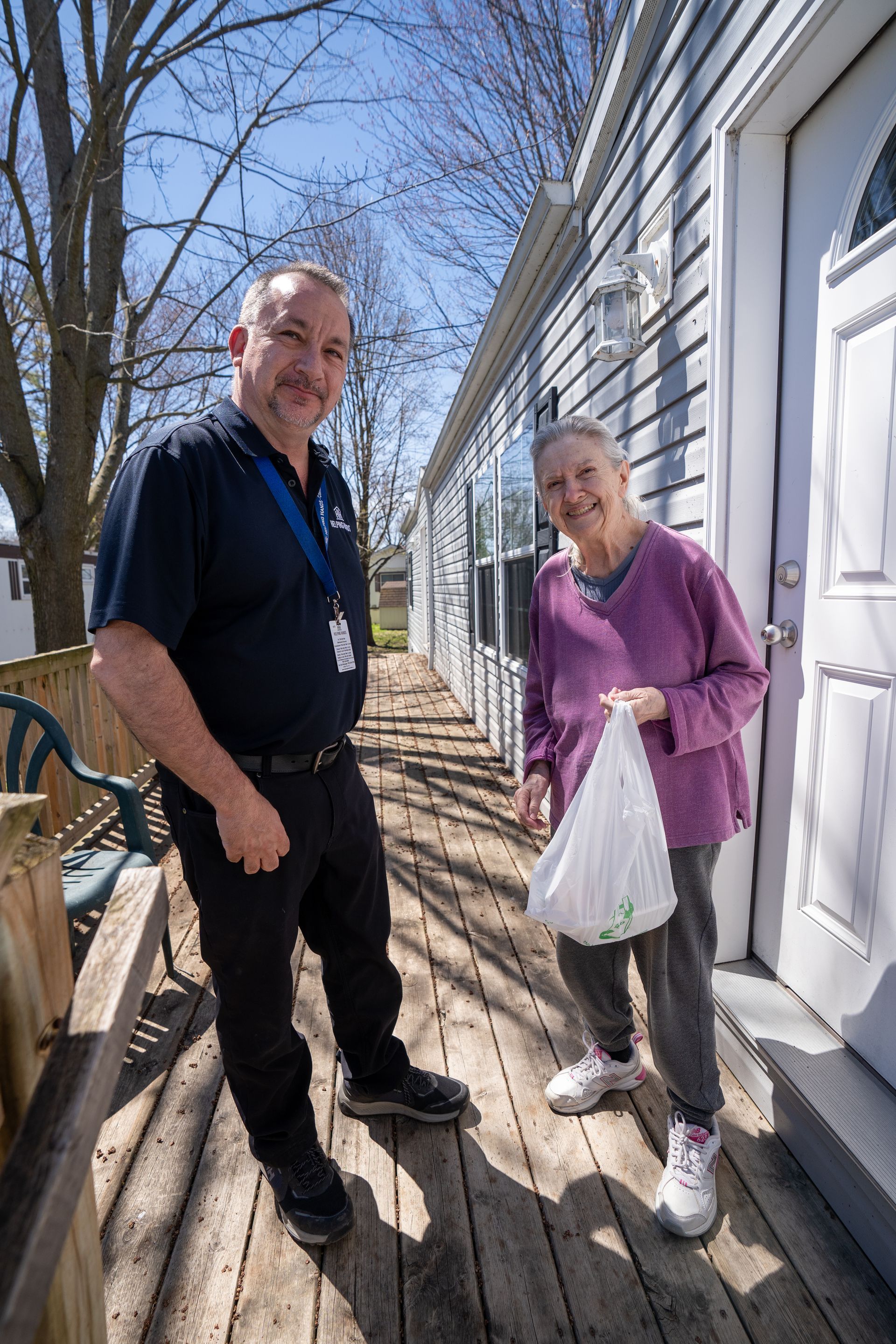 A man and a woman are standing on a deck in front of a house.