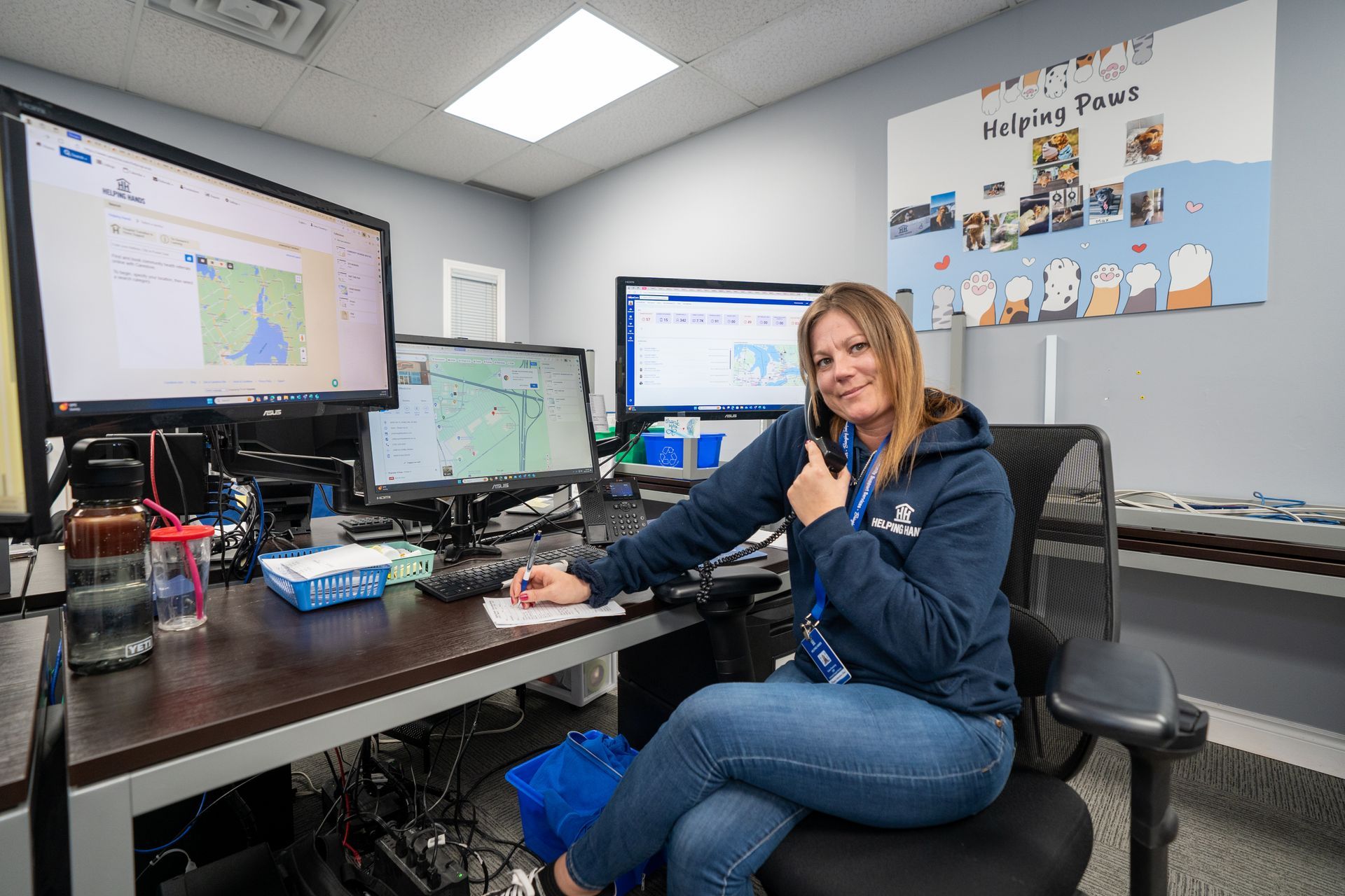 A woman is sitting at a desk talking on a cell phone.