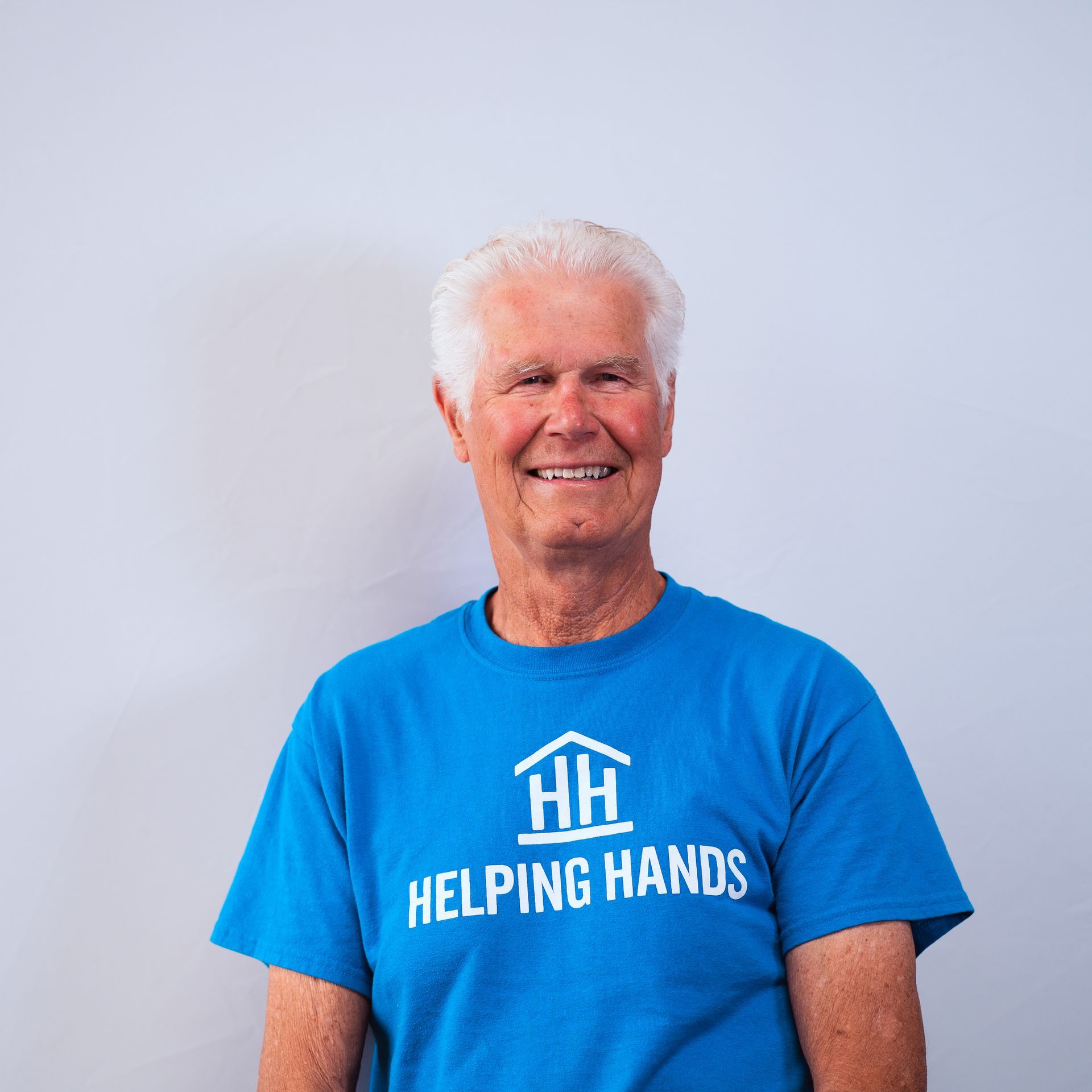 A man wearing a blue shirt that says helping hands