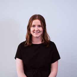 The woman is wearing a black shirt and smiling for the camera.