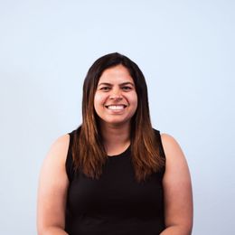 A woman in a black tank top is smiling for the camera