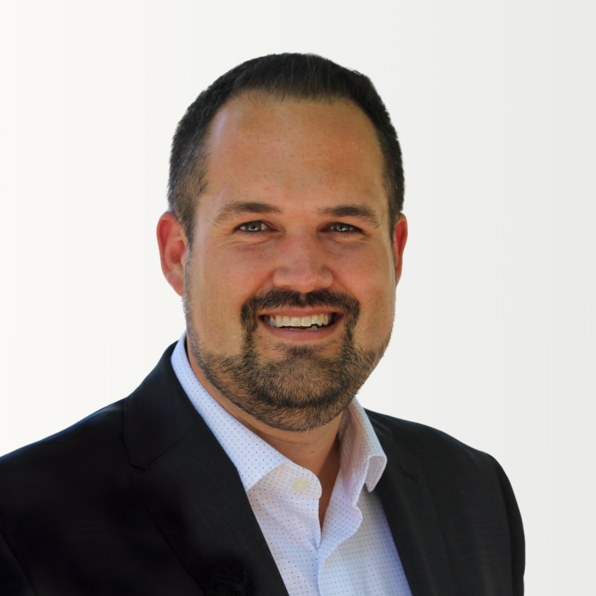 A man in a green striped shirt is standing in front of a white wall.