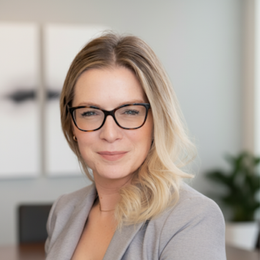 A man in a green striped shirt is standing in front of a white wall.