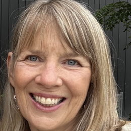 A man in a green striped shirt is standing in front of a white wall.