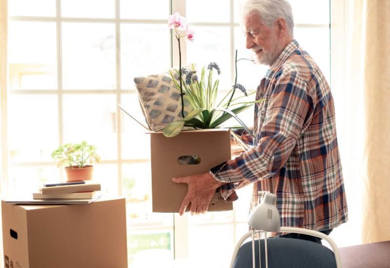 Older adult carrying a box 