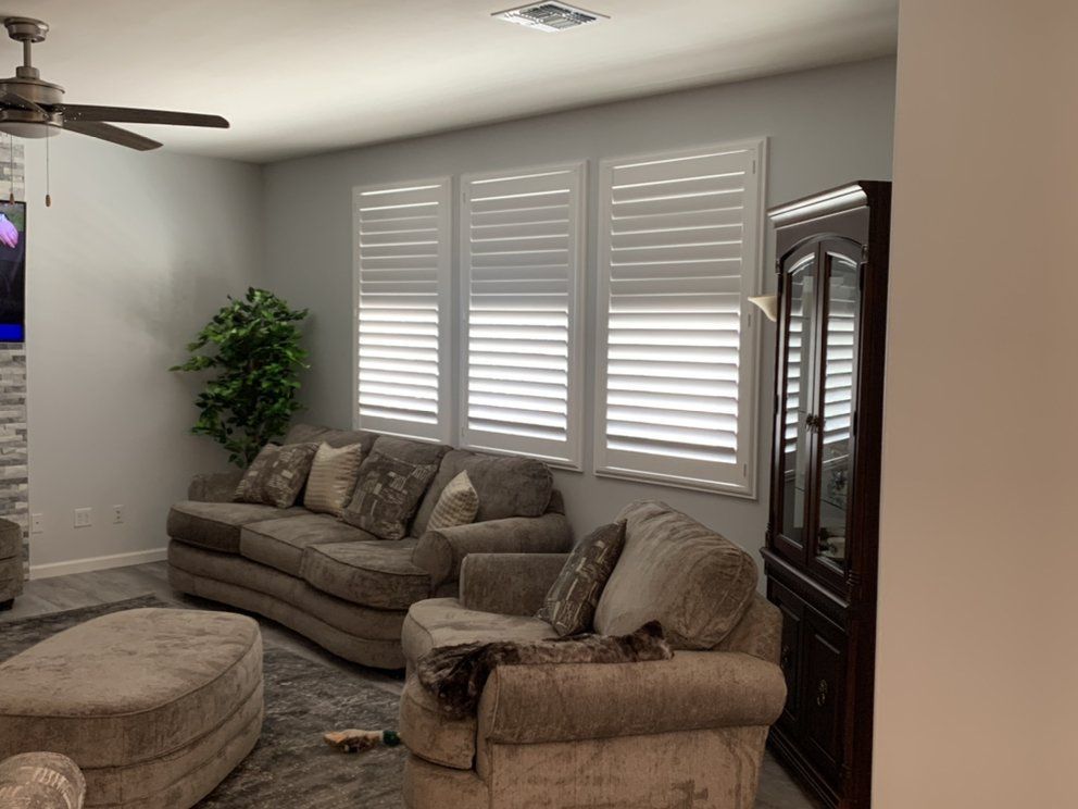 Living room with gray walls, beige sofa, white shutters, and a dark brown cabinet.