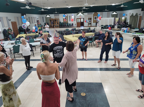 A group of people are dancing in a large room.