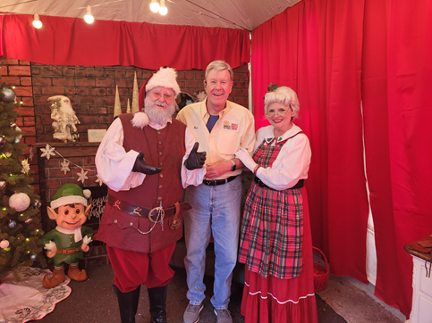 A man and two women are posing for a picture with santa claus.