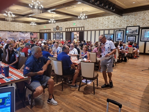 A large group of people are sitting at tables in a large room.