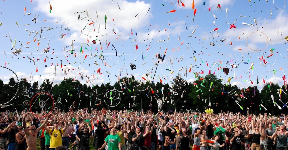 A crowd of people are standing in a field with confetti flying in the air.