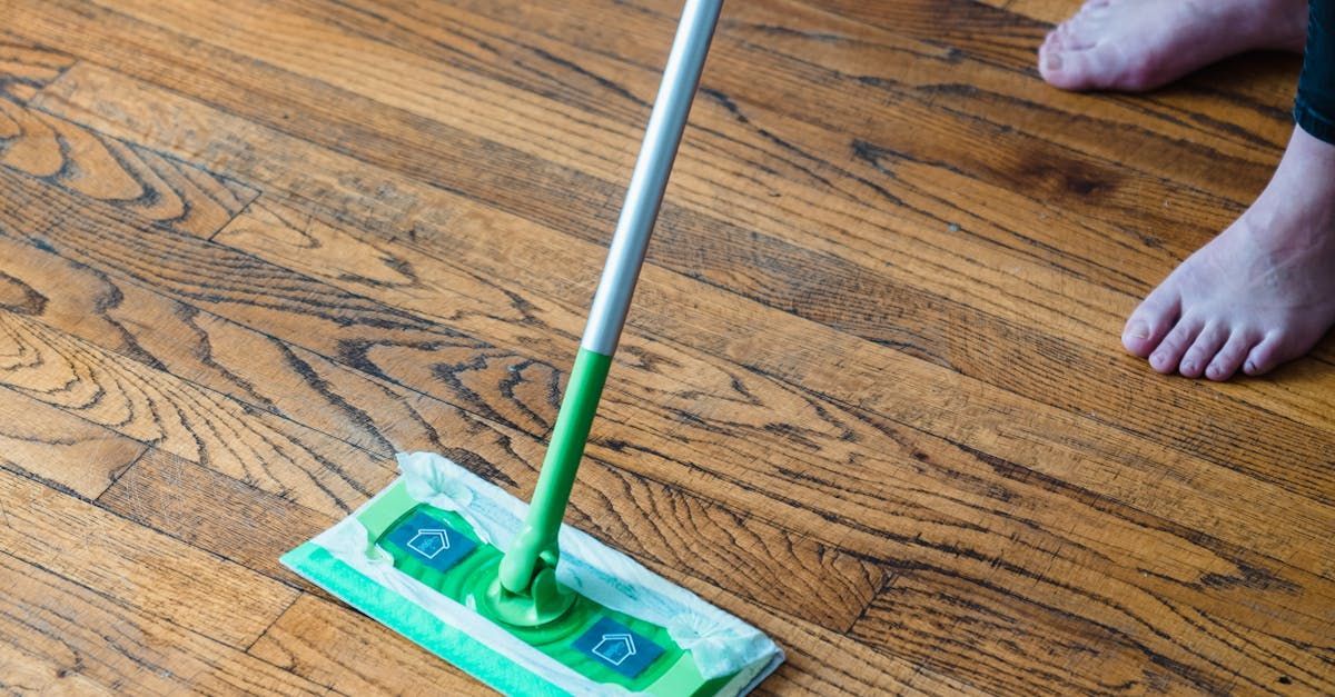 A person is cleaning a wooden floor with a mop.