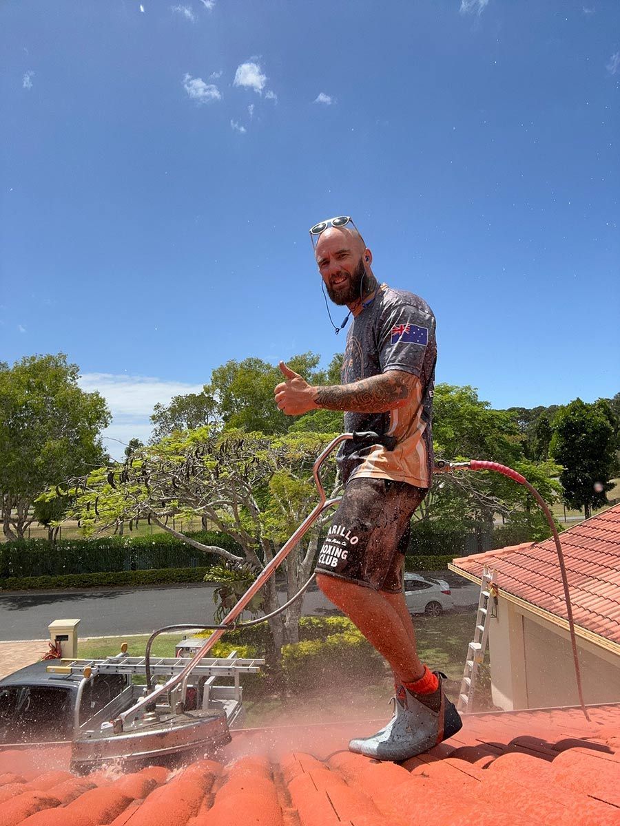 A Man Is Standing On Top Of A Roof With A Machine — Clean Cartel Pressure Washing In Reedy Creek, QLD