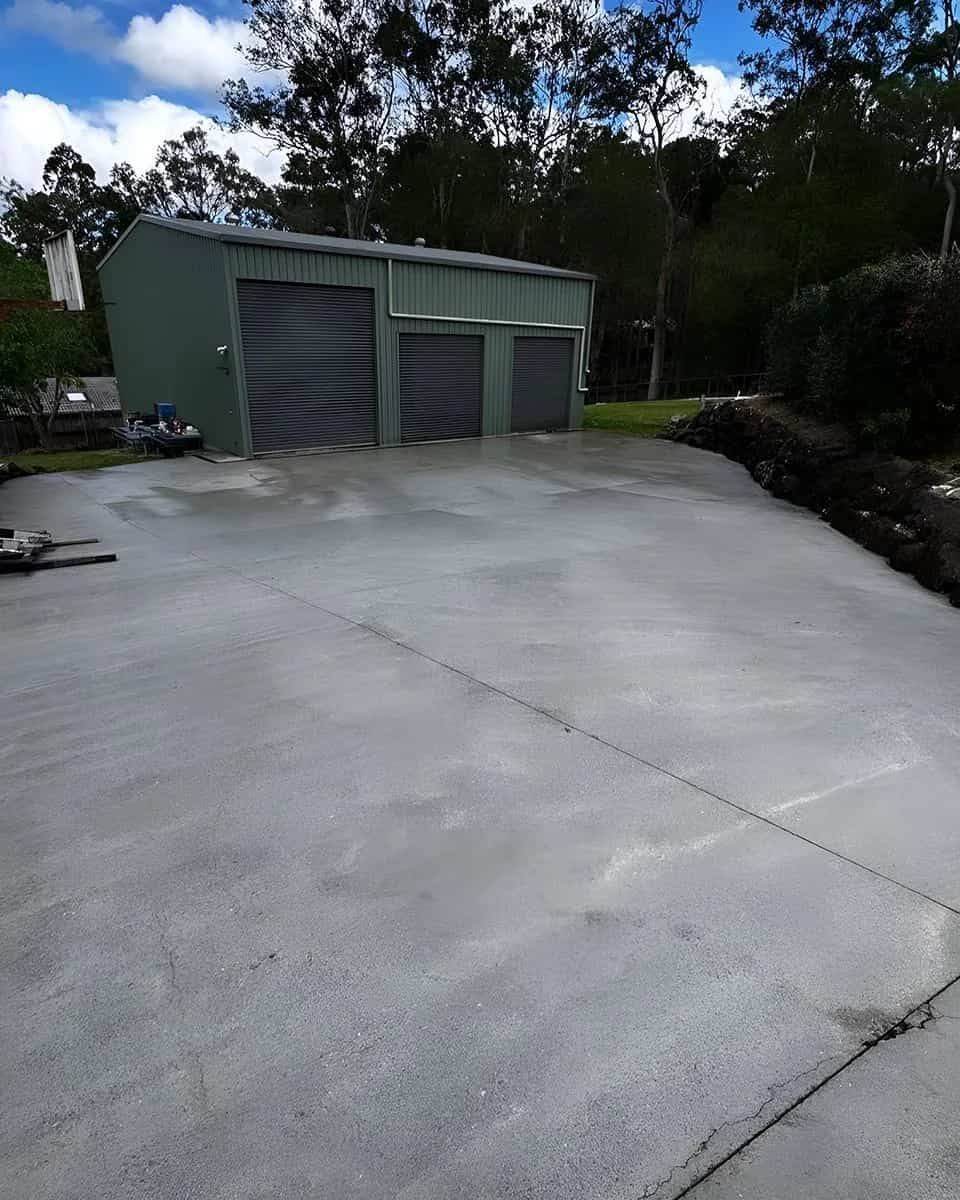 A Concrete Driveway Leading to A Garage with Three Garage Doors — Clean Cartel Pressure Washing In Reedy Creek, QLD
