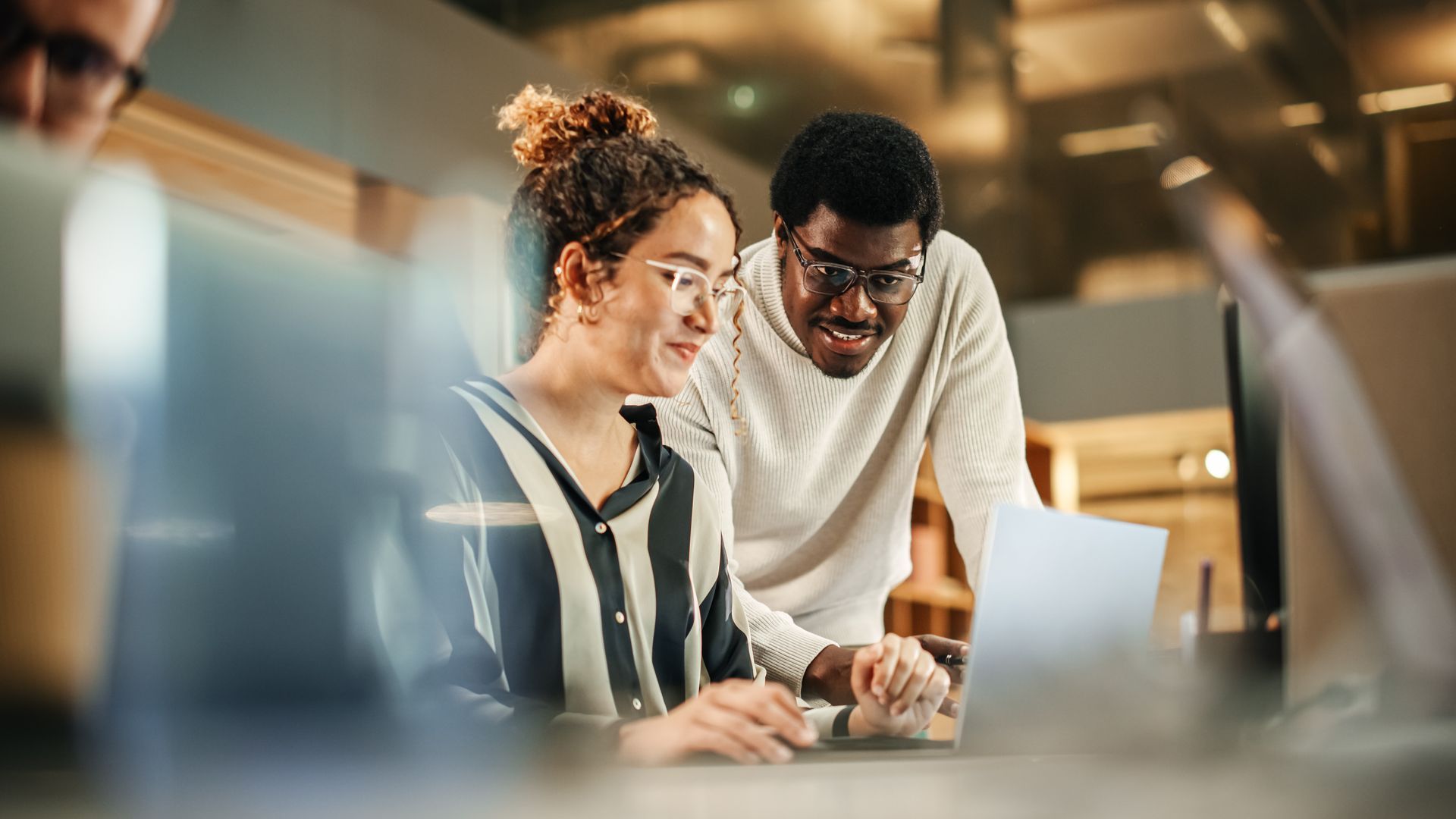 A man and a woman are looking at a laptop computer.