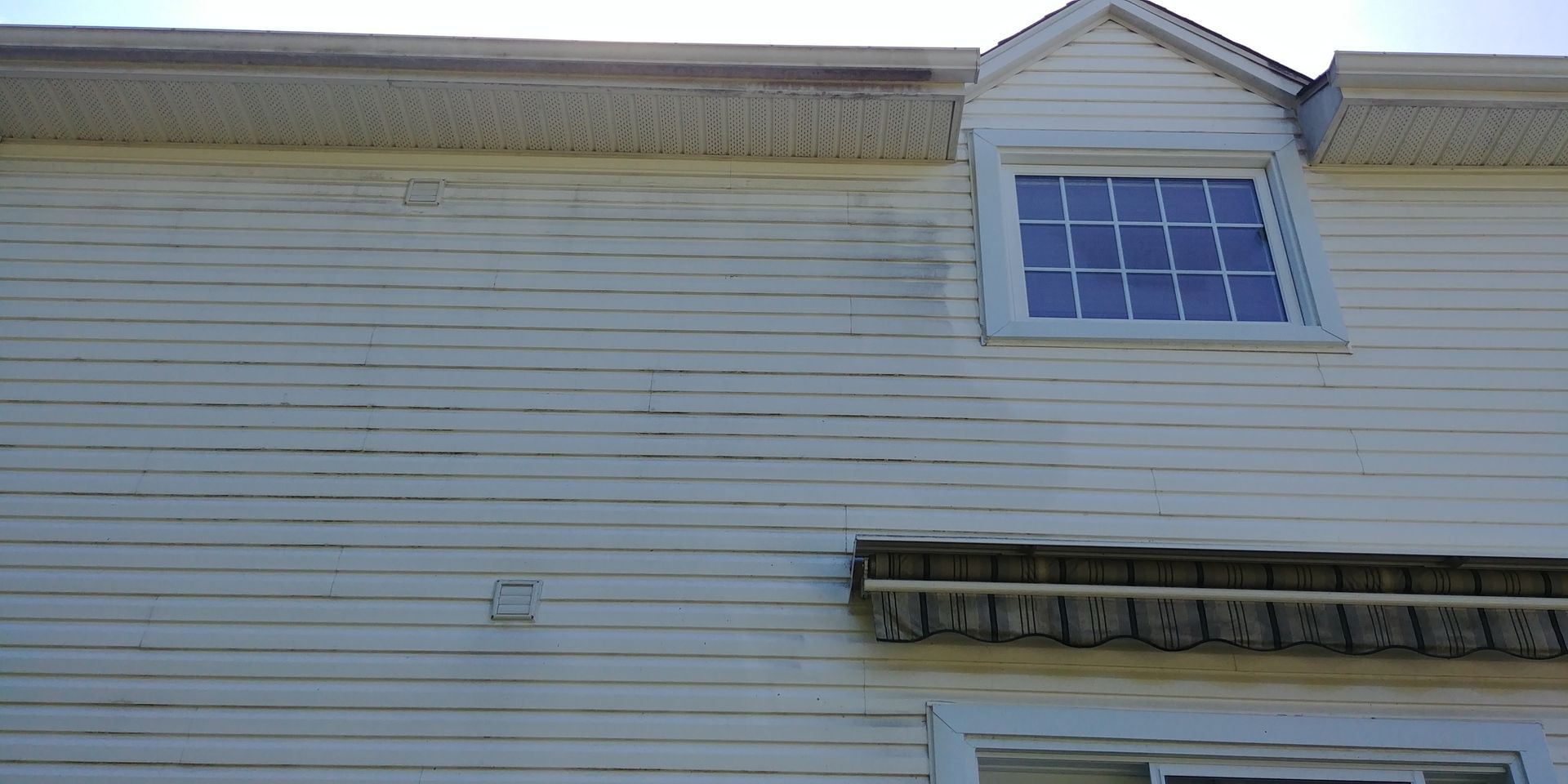 Une maison blanche avec une fenêtre et un toit