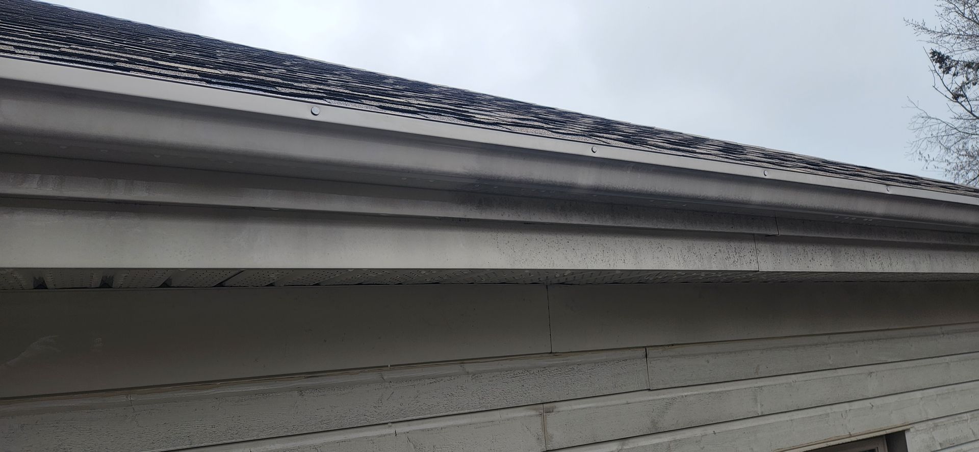 Une maison blanche avec un toit noir et une bordure blanche.