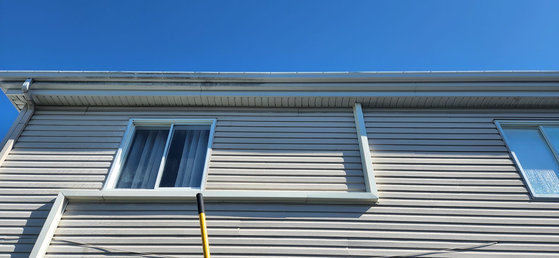 Une maison avec beaucoup de fenêtres et un ciel bleu en arrière-plan.