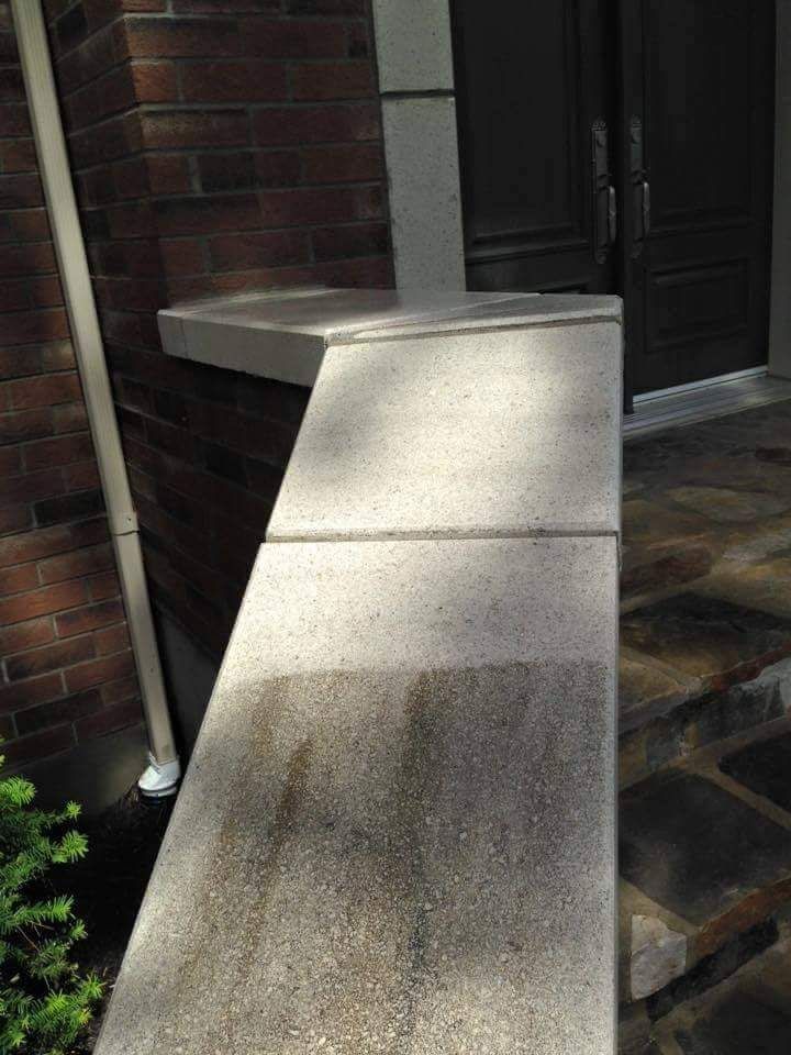 Une passerelle en béton menant à une porte à côté d'un mur de briques.