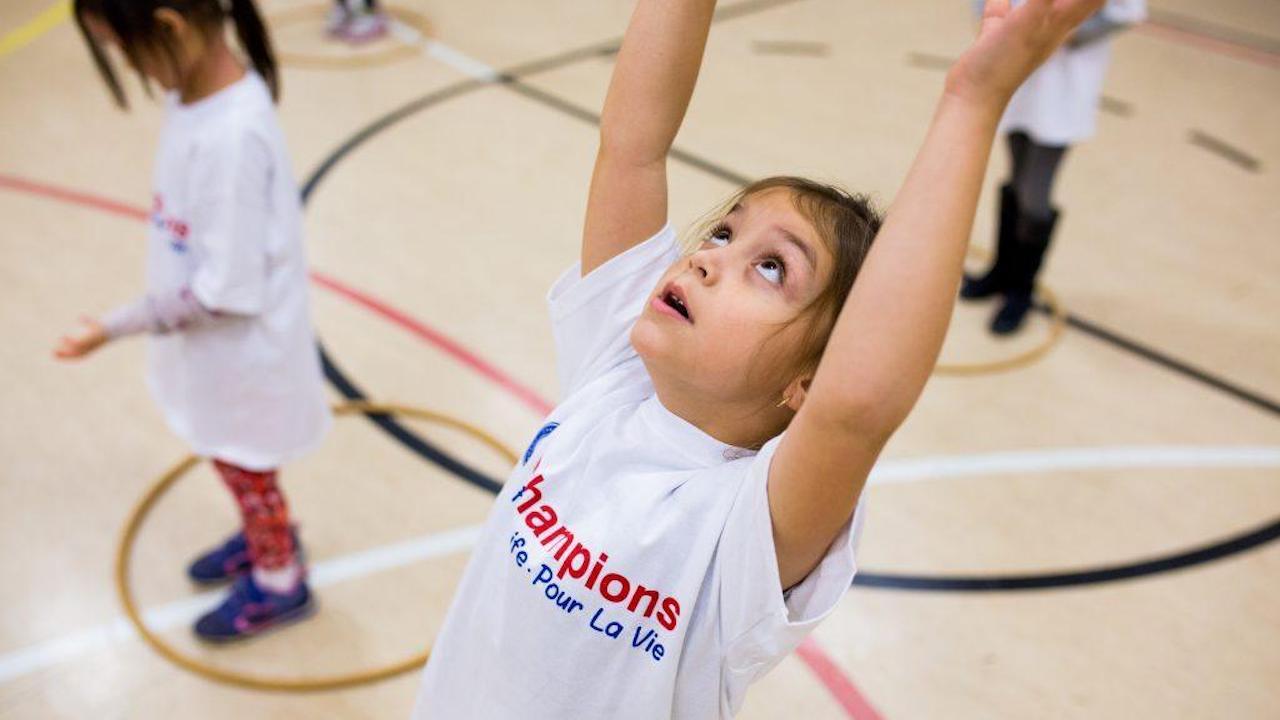 A young girl wearing a shirt that says champions is playing basketball