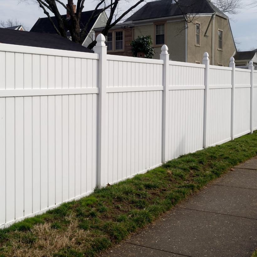 A white fence along a sidewalk in front of a house