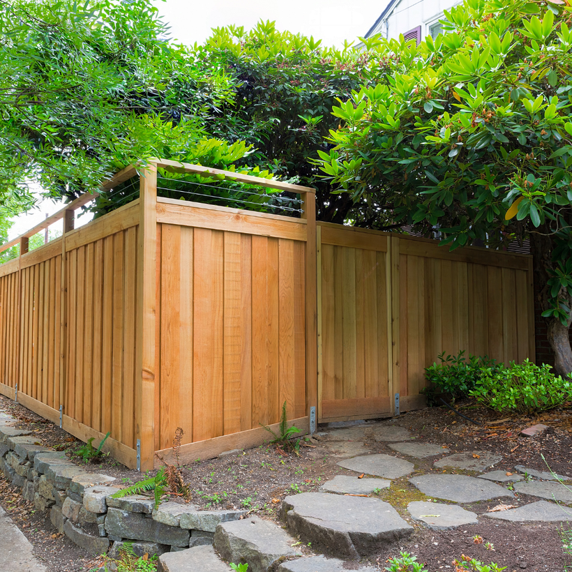 A wooden fence is surrounded by trees and a stone walkway.