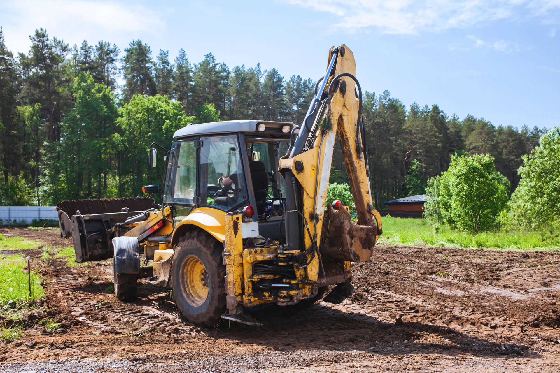 A man is driving a tractor through a grassy field.