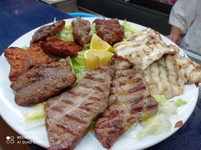 Un piatto bianco condito con una varietà di carni e lattuga