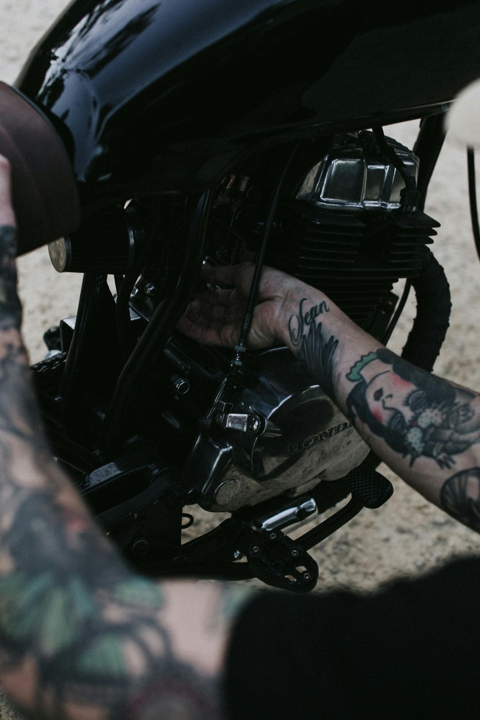 A man with tattoos working on a motorcycle