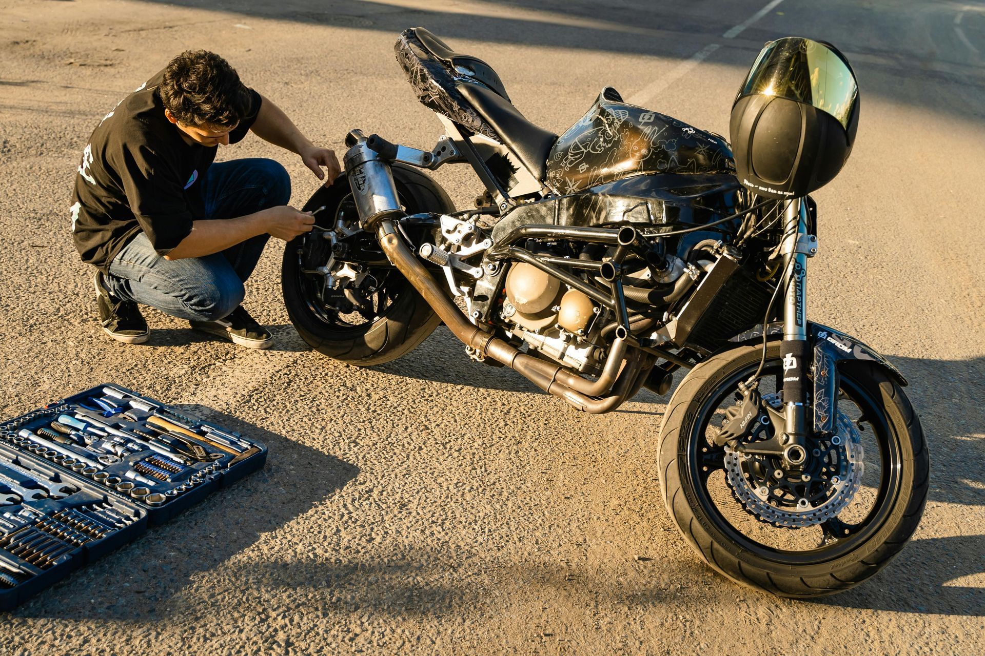 A man working on a motorcycle in a parking lot.