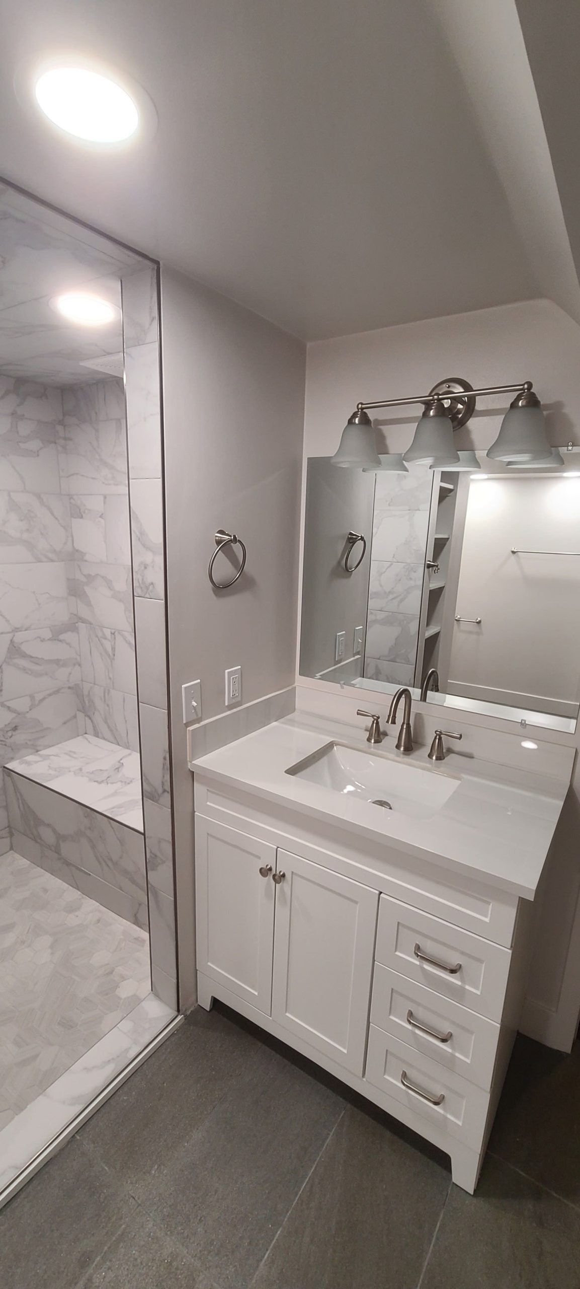 Bathroom with a white vanity, mirror, and a marble shower stall.